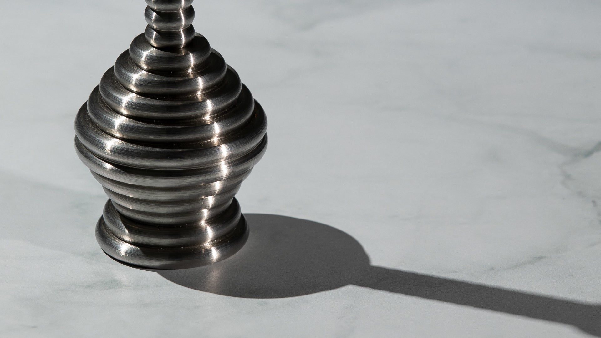Zoom on the base of the design piece, with its reflective metal and its casted shadow